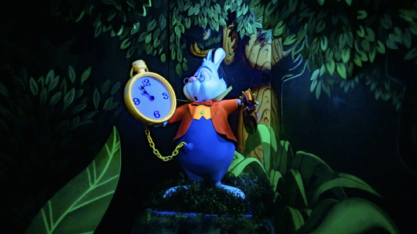 Un lapin blanc animé, tenant une grande montre de poche, se tient au milieu d'un feuillage vert, le regard tourné vers le ciel, l'air inquiet, rappelant l'ouverture emblématique d'Alice au pays des merveilles du 14 juin 1958.