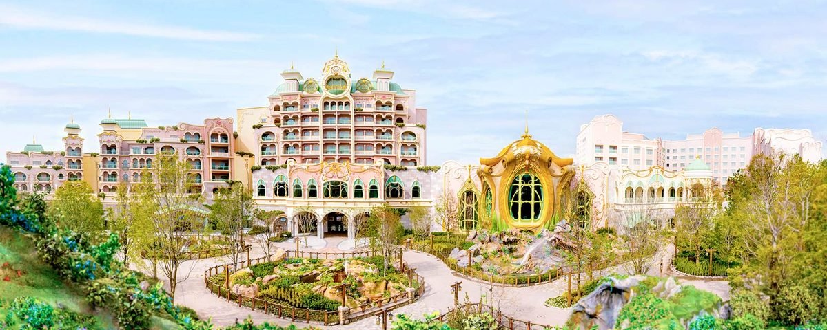 Des bâtiments colorés et fantaisistes aux motifs raffinés, entourés d'espaces verts sous un ciel bleu, avec au centre un édifice surmonté d'un dôme et un jardin au premier plan : ce cadre charmant évoque l'ambiance magique que vous retrouverez dans un hébergement à Tokyo Disneyland, idéal pour les familles en quête de souvenirs inoubliables à deux pas du parc.