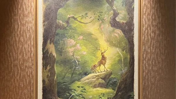 Tableau encadré représentant un cerf et son faon debout sur un rocher dans une forêt baignée de soleil, qui rappelle les « tableaux exclusifs » que l'on trouve dans les « chambres rénovées » du Disney Sequoia Lodge, accroché sur un mur à motifs sous des spots.