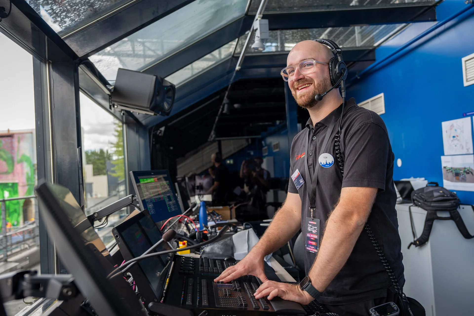 Un homme portant un casque audio pilote le matériel sonore et d'éclairage depuis une régie aux parois vitrées, entouré d'écrans et d'équipements techniques, au sein des équipes SFX chargées de créer de superbes effets spéciaux à Disneyland Paris.
