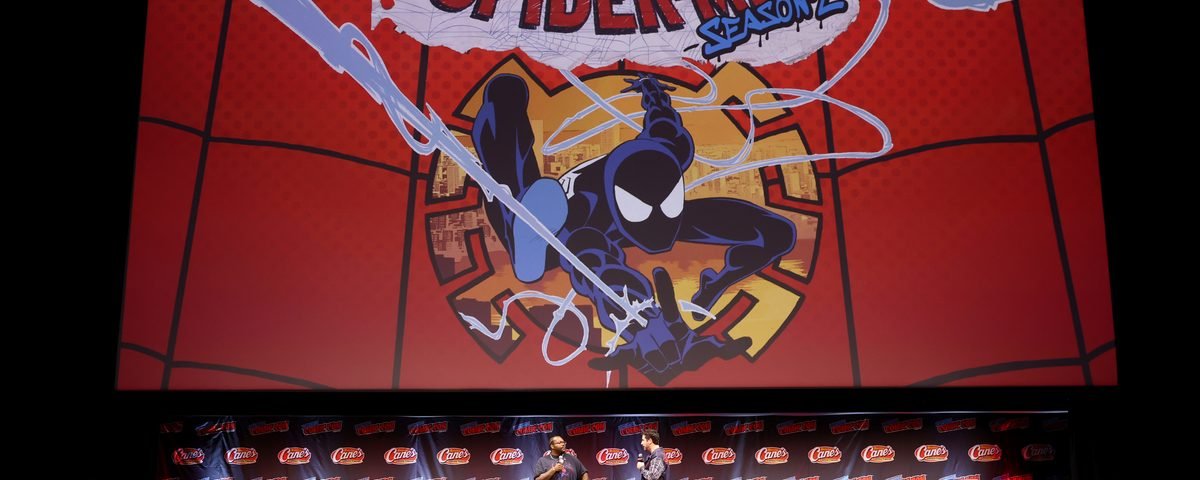 Deux personnes sur la scène du Comic Con, devant un grand écran affichant le logo de la saison 2 de la série « Your Friendly Neighborhood Spider-Man » de Marvel.