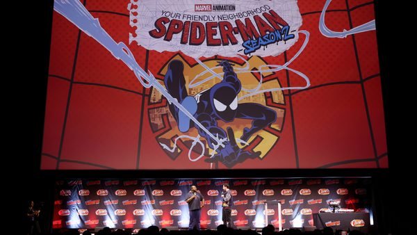 Deux personnes sur la scène du Comic Con, devant un grand écran affichant le logo de la saison 2 de la série « Your Friendly Neighborhood Spider-Man » de Marvel.