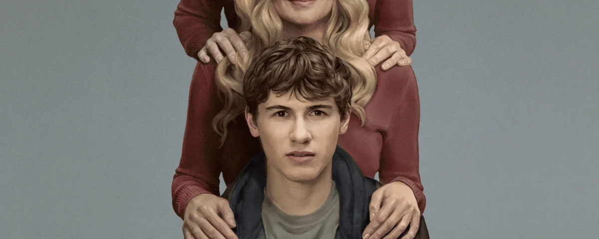 Dans cette scène de la série « Phony », une femme blonde se tient derrière un jeune homme, les mains posées sur ses épaules.